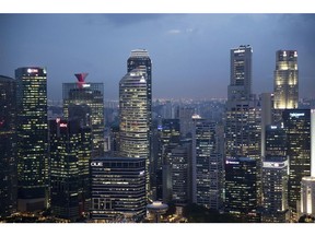 Commercial buildings in the central business district are illuminated at dusk in Singapore, on Wednesday, June 13, 2018. Tourism as well as the consumer sector will likely see a lift thanks to the influx of international media at the recent DPRK-USA Summit, according to RHB Research Institute Singapore Pte. Photographer: Brent Lewin/Bloomberg