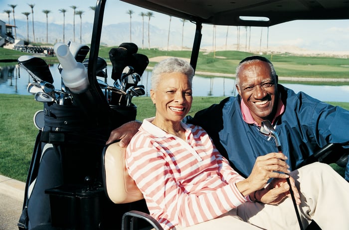Smiling couple sitting on golf cart.